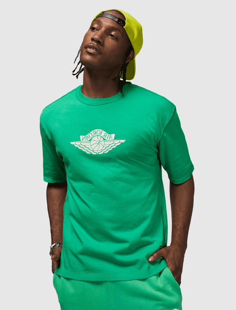 Man wearing green Air Jordan t-shirt and shorts with neon cap, streetwear outfit