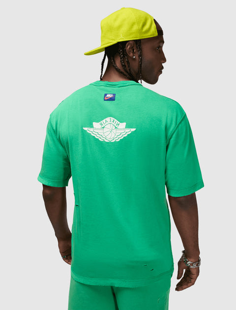 Man wearing green Nike Air t-shirt and shorts set, with lime green cap, shown from the back