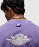 Back view of man wearing a purple Nike Air streetwear tee with basketball wings logo