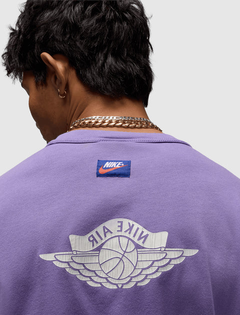 Back view of man wearing a purple Nike Air streetwear tee with basketball wings logo