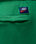 Close-up of green sweatpants pocket with Nike logo patch above the seam