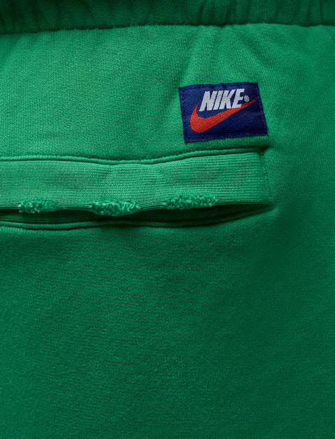 Close-up of green sweatpants pocket with Nike logo patch above the seam
