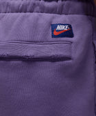 Close-up of purple Nike sweatpants back pocket with elastic waistband and logo patch