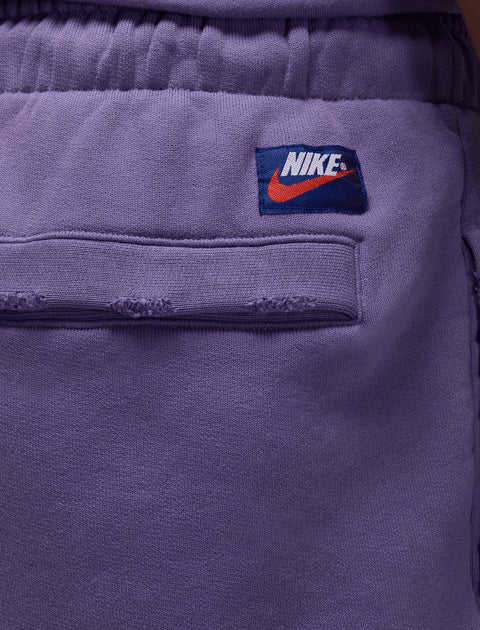 Close-up of purple Nike sweatpants back pocket with elastic waistband and logo patch