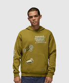 Man wearing olive green graphic streetwear hoodie with white illustrations and blue pants