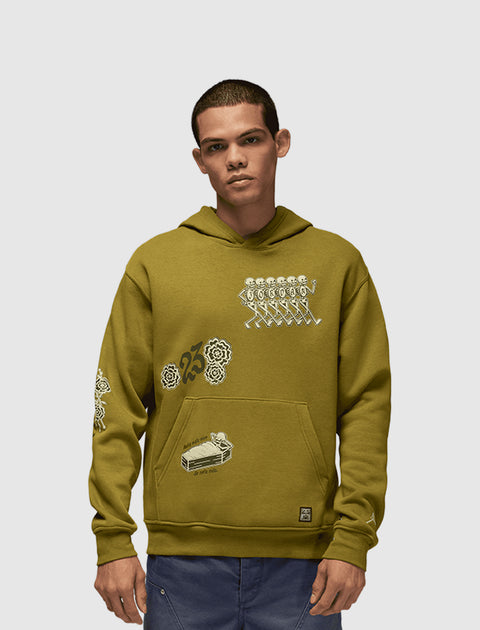 Man wearing olive green graphic streetwear hoodie with white illustrations and blue pants