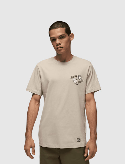 Man wearing beige streetwear t-shirt with chest graphic text and hand illustration