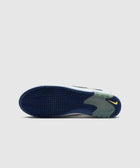 Bottom view of a sneaker with blue textured sole, green heel accent, and yellow Nike Swoosh logo