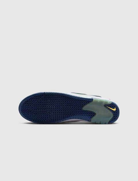 Bottom view of a sneaker with blue textured sole, green heel accent, and yellow Nike Swoosh logo