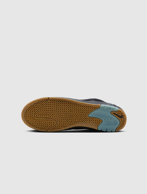 Gum sole of a black sneaker with herringbone tread and blue grip panel on a white background