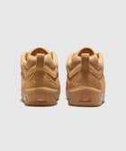 Tan suede skate sneakers with gum soles, viewed from the back, on light gray background.