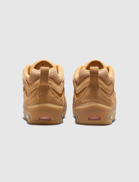 Tan suede skate sneakers with gum soles, viewed from the back, on light gray background.