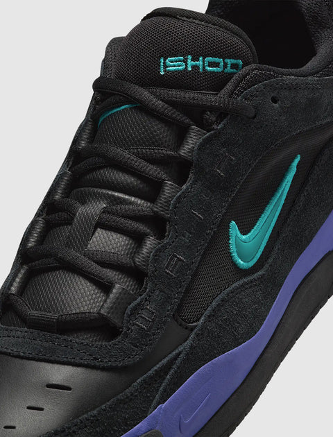 Black sneaker with teal logo, purple midsole, mesh tongue, and suede accents, close-up view