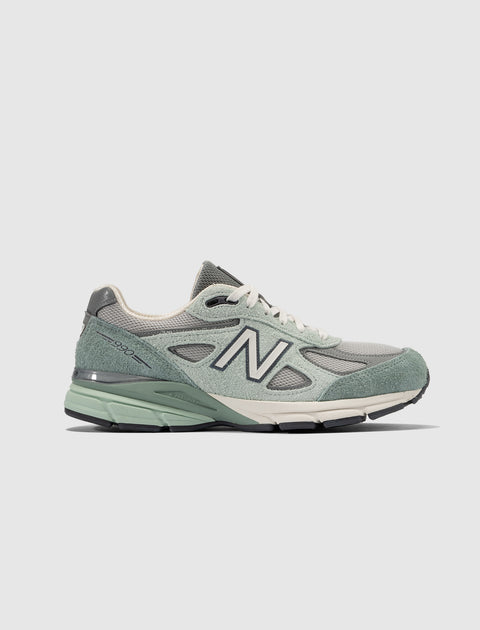 Side view of grey and green suede mesh men's streetwear sneaker on white background