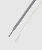 Close-up of grey and white flat sneaker laces on a light background