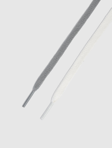 Close-up of grey and white flat sneaker laces on a light background