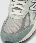 Close-up of a grey and mint green mesh and suede sneaker with white laces