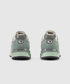 Back view of green and grey New Balance sneakers with suede details on white background