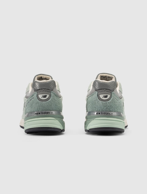 Back view of green and grey New Balance sneakers with suede details on white background