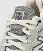 Close-up of New Balance 990v4 sneaker with grey mesh, suede details and white laces