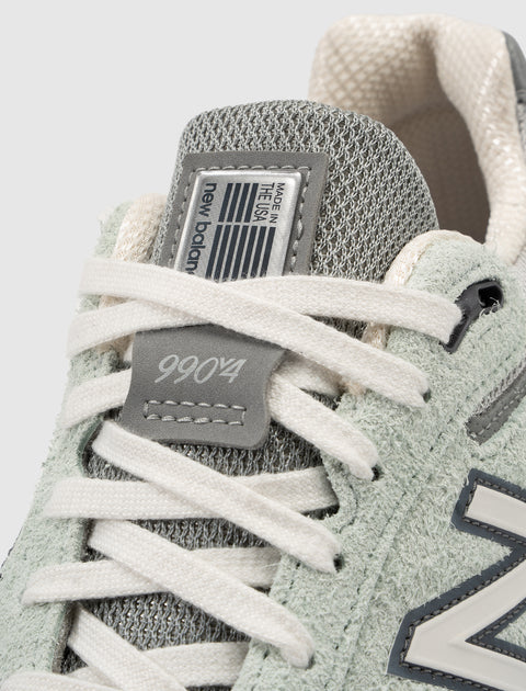 Close-up of New Balance 990v4 sneaker with grey mesh, suede details and white laces