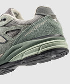 Close-up of mint green and grey suede men's sneaker with 990 logo and textured sole