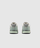 Rear view of grey and green New Balance sneakers on a light background