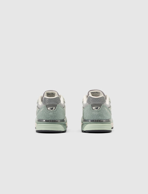 Rear view of grey and green New Balance sneakers on a light background