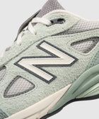 Close-up of pastel green and grey suede sneaker with mesh panels and lace-up design