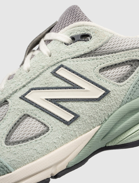 Close-up of pastel green and grey suede sneaker with mesh panels and lace-up design
