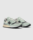 Mint green and black suede sneakers with beige accents on a white background