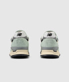 Rear view of pale green suede sneakers with white and black heel detail, casual footwear