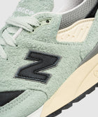 Close-up of mint green suede sneaker, textured upper, mesh details, black N logo patch