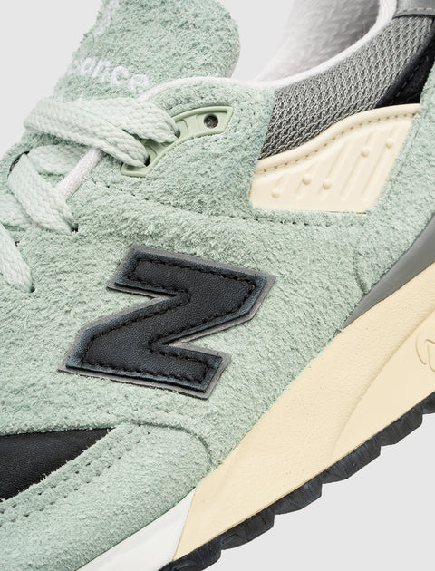 Close-up of mint green suede sneaker, textured upper, mesh details, black N logo patch