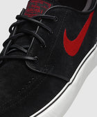 Black suede skate shoe with red swoosh logo, white sole, and black laces