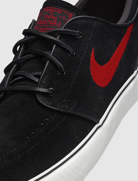 Black suede skate shoe with red swoosh logo, white sole, and black laces