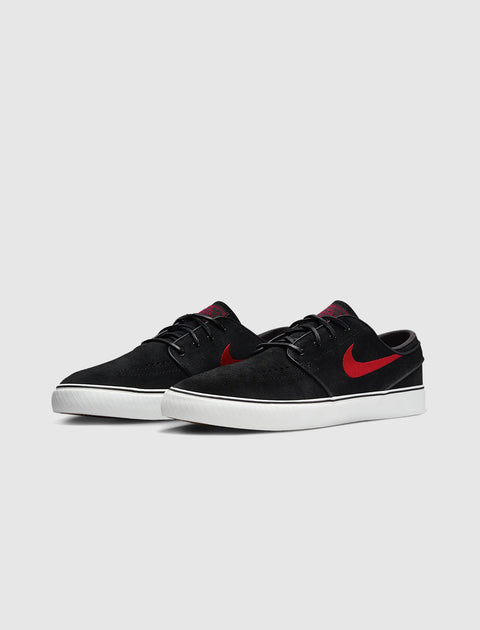 Black suede low-top sneakers with red swoosh and white sole on a plain background