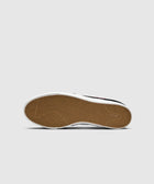 Close-up of sneaker gum sole with herringbone tread pattern on a light background