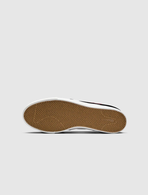 Close-up of sneaker gum sole with herringbone tread pattern on a light background