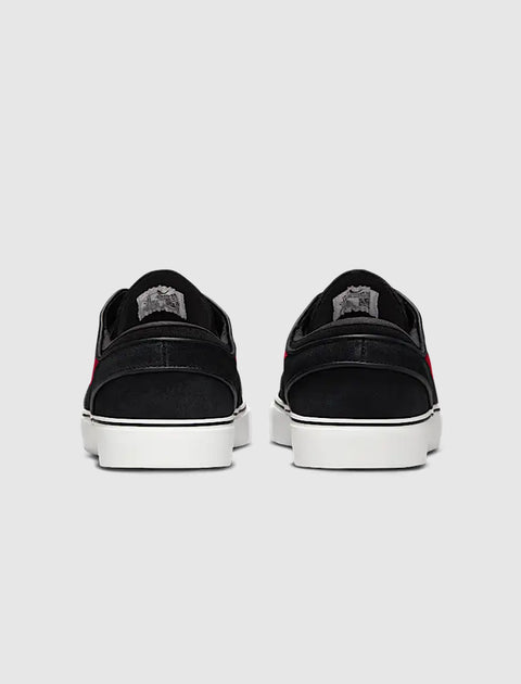 Back view of black streetwear sneakers with white soles and red accents on a neutral background