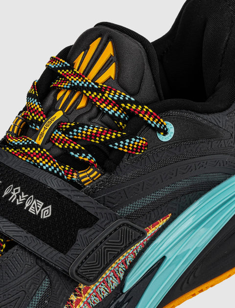 Close-up of black sneaker with multicolor laces, yellow tongue design, blue midsole