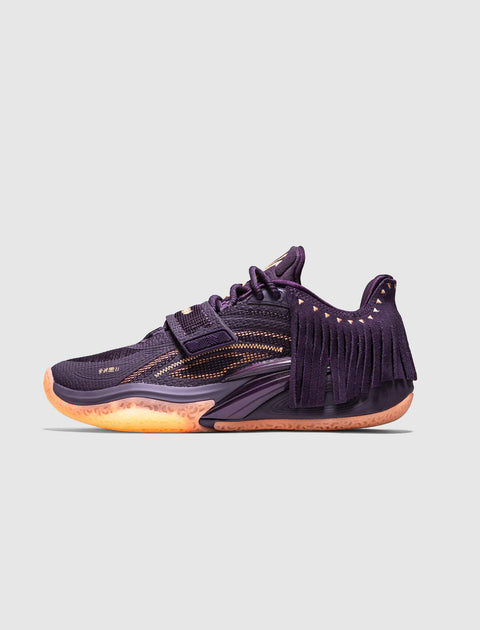 Purple low-top sneaker with mesh details, side fringe, and orange sole on plain background