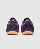Purple suede sneakers with fringe and orange textured soles, rear view on white background