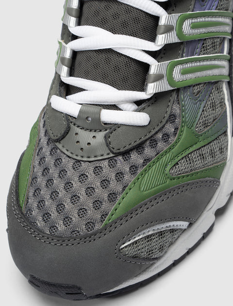 Close-up of men's grey mesh sneaker with green accents and white laces.
