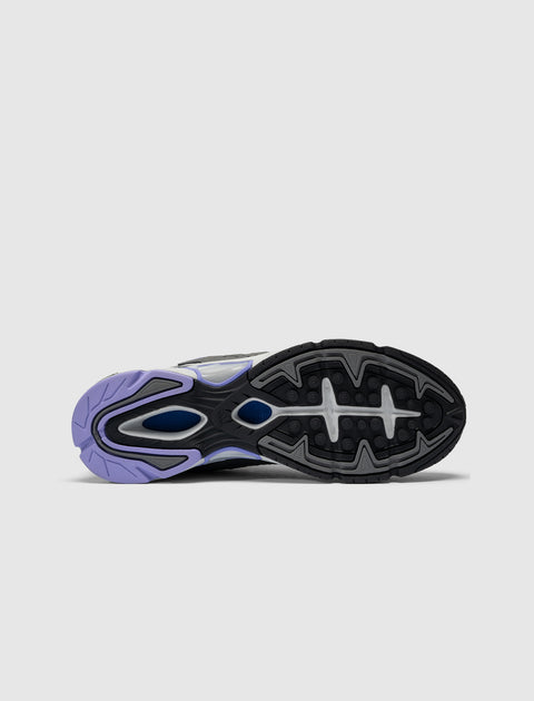 Sole view of a grey, green, and purple men's sneaker with textured grip pattern