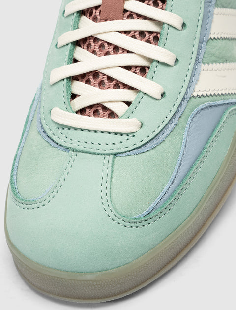 Close-up of mint green suede sneaker with white laces and mesh tongue