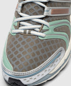 Close-up of brown mesh sneaker with white laces, mint and blue accents, rubber sole