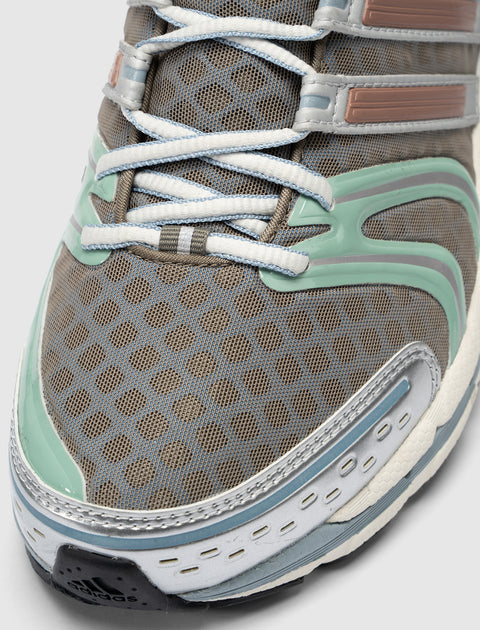 Close-up of brown mesh sneaker with white laces, mint and blue accents, rubber sole
