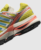 Yellow and beige sneaker with blue accents, mesh upper, and textured rubber sole, side view