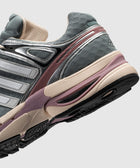Close-up of grey mesh sneaker with silver, purple, and beige accents on textured sole